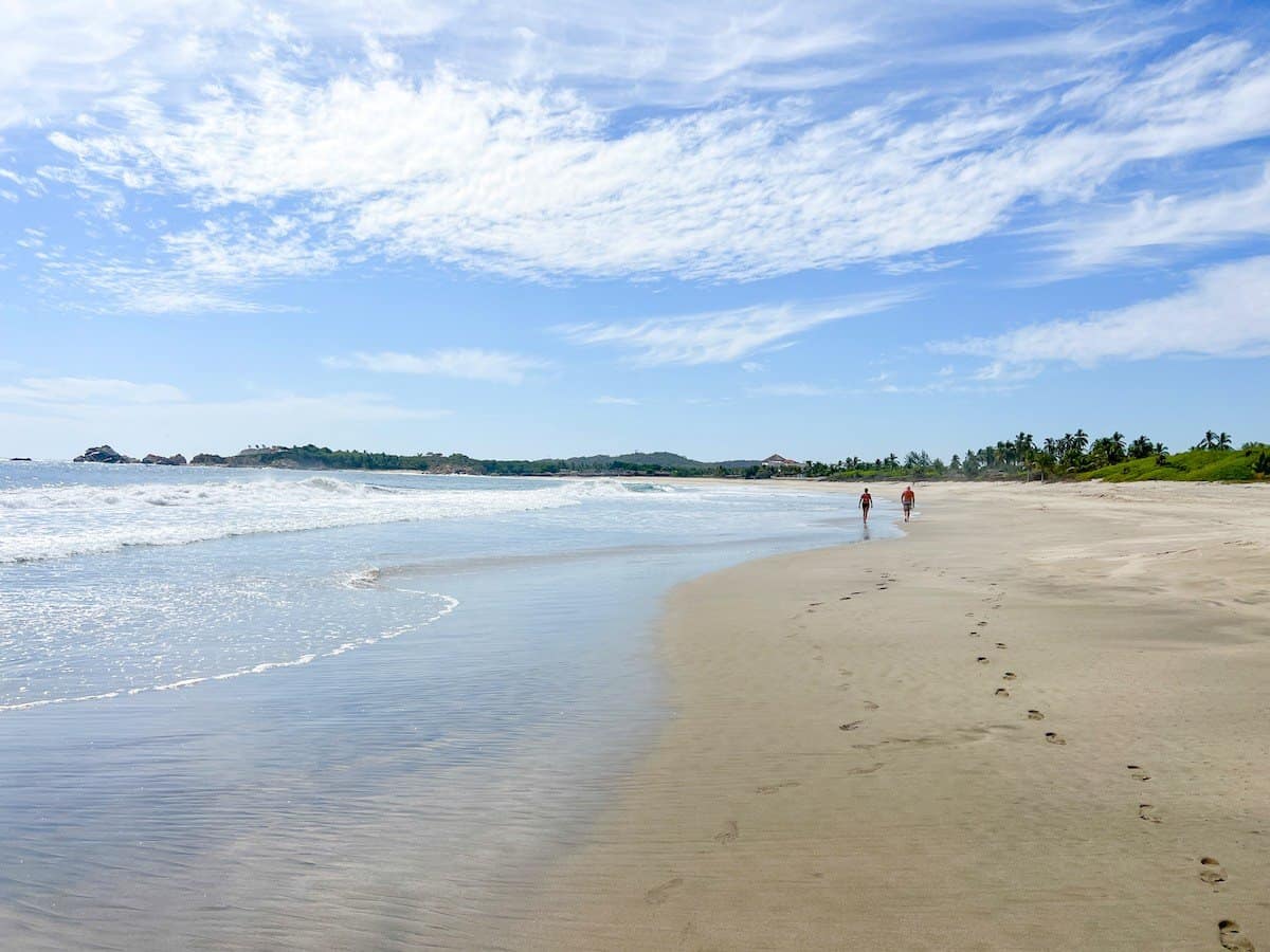 Two people walking on Playa Roca Blanca in Oaxaca, Mexico.