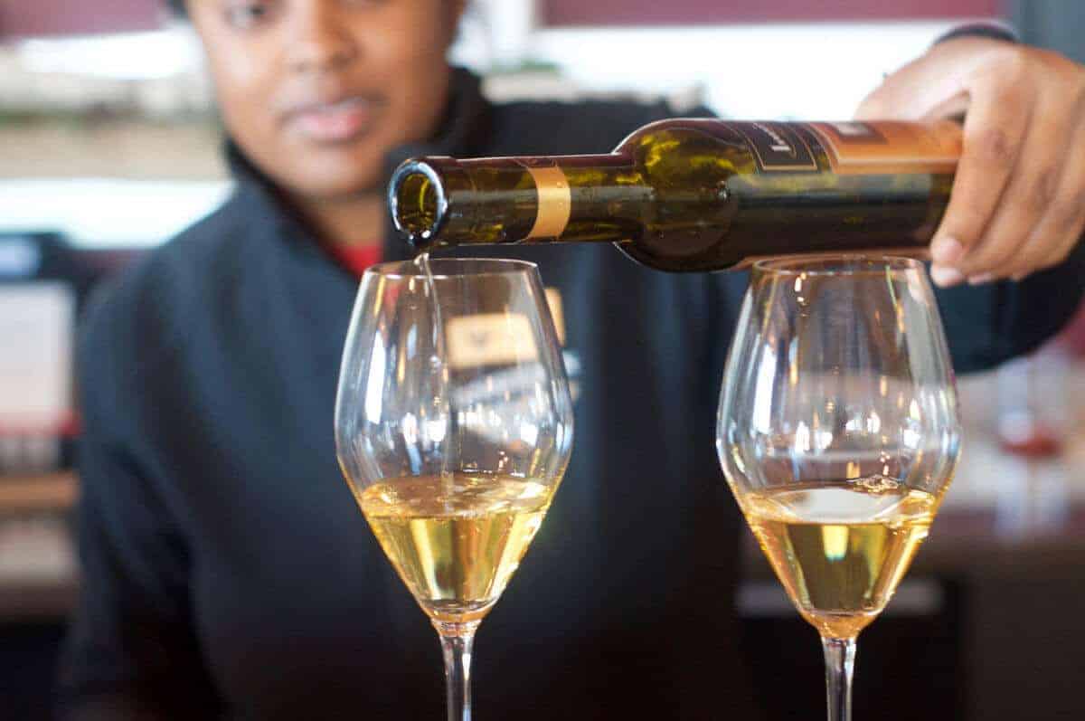 Woman pouring ice wine in a wine glass.