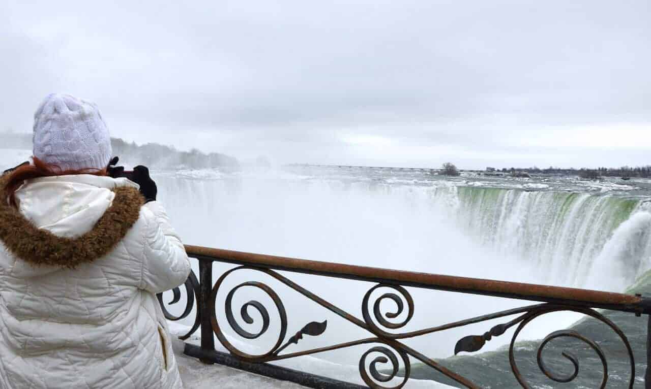 Tourist taking a photo of Niagara Falls in the winter.