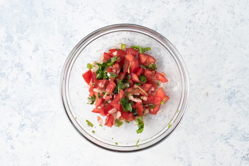 Salsa Fresca or pico de gallo in a clear glass bowl. 