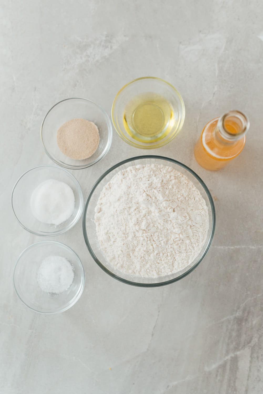 Ingredients for making beer pizza dough including salt, white sugar, olive oil, all-purpose flour, beer and yeast.