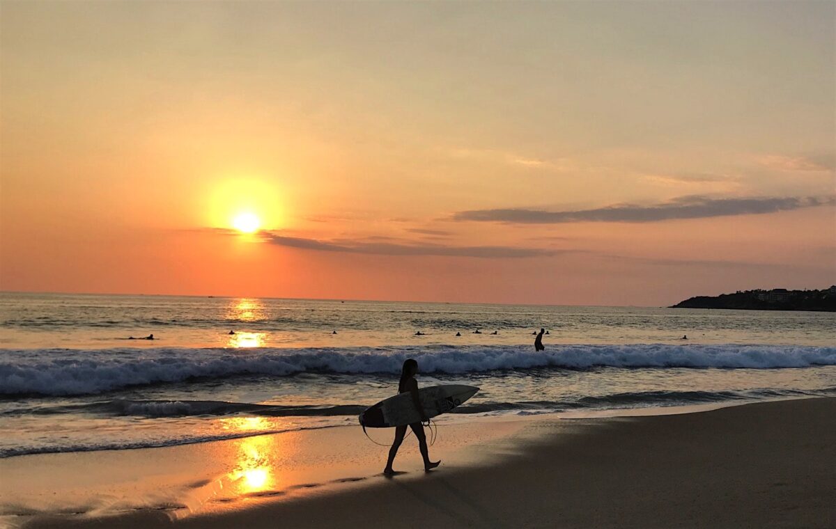 Surfer at sunset on the beach in Puerto Escondido Oaxaca.