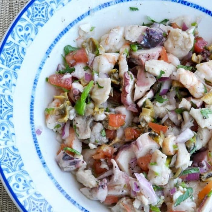 Ceviche Mixto made with a mix of raw seafood served in a white and blue dish. 