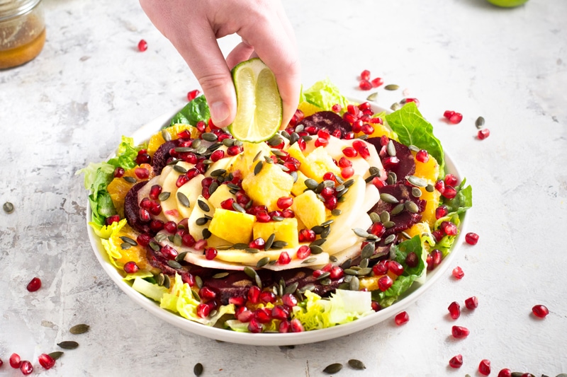 Person squeezing ensalada de nochebuena with fresh lime juice.