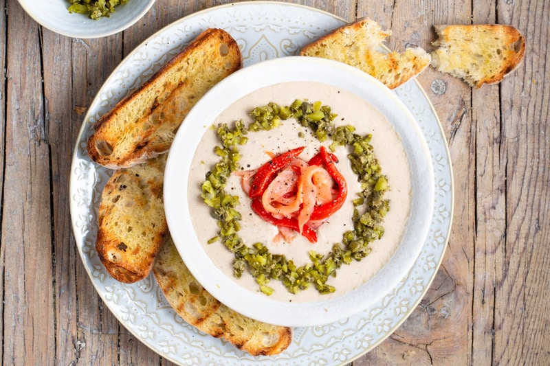 Overhead shot of crostini with a Cream of Sardine Pate by Martin Berasategui for Gastro Bar on a wooden table. 