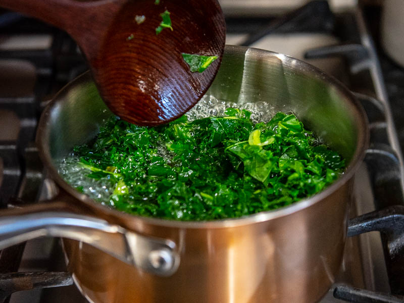 Fresh chicory boiling in a copper pot for fave e cicoria.
