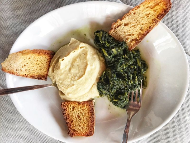 Purè di fave e cicorie or Fava Bean Purée with Chicory on a white plate with crostini.