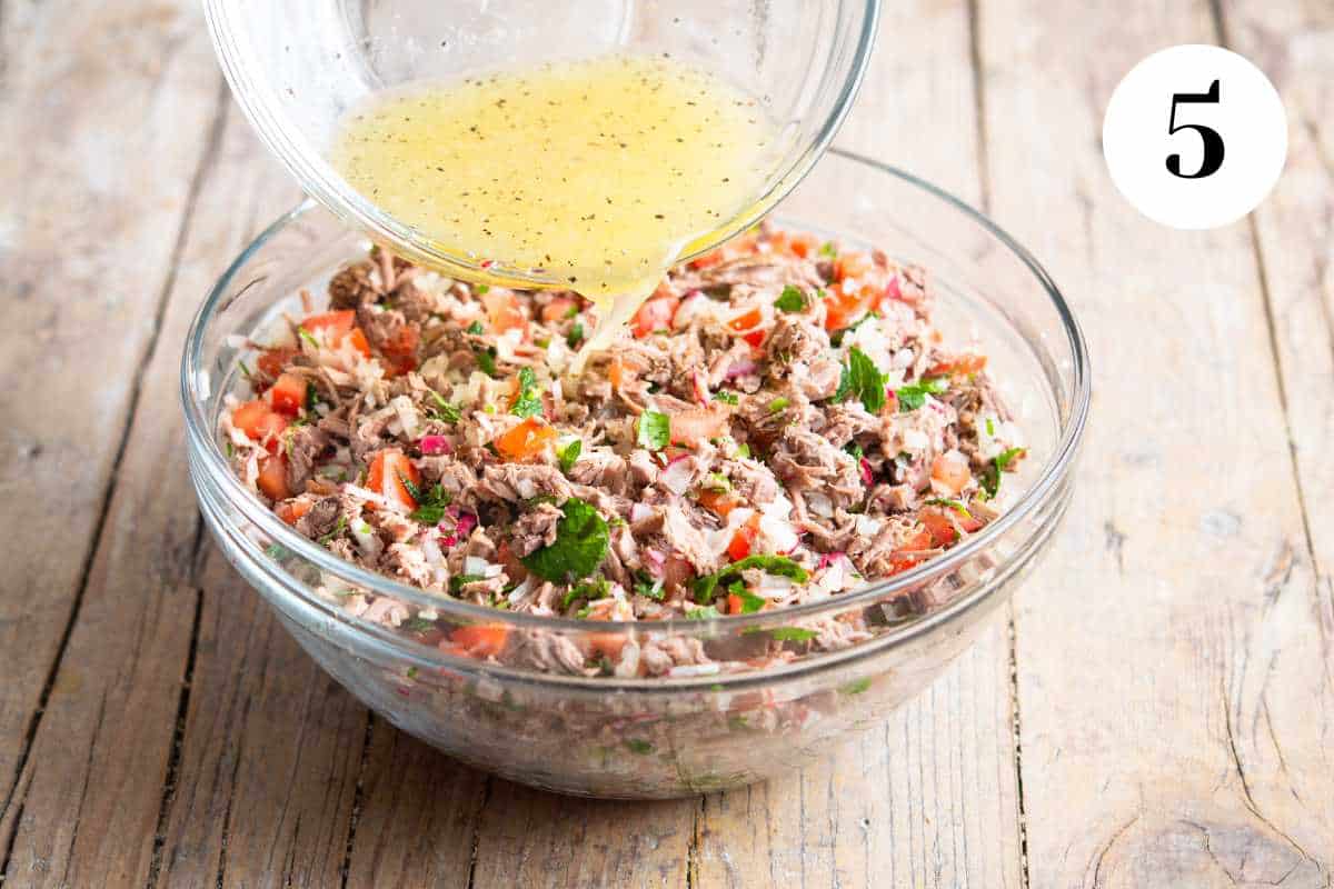 Pouring the vinaigrette dressing over the shredded beef salad.