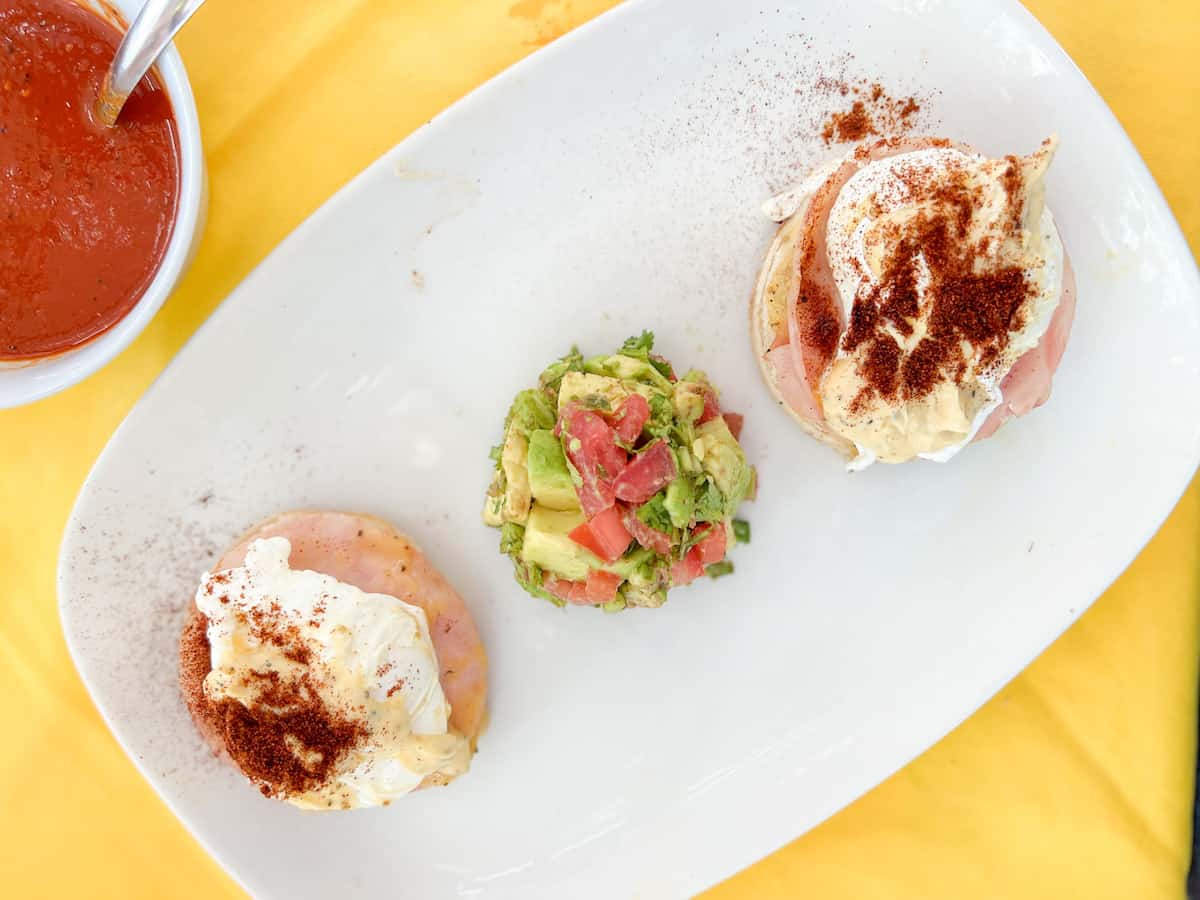 Eggs Benedict in Puerto Escondido on a white plate set on a yellow tablecloth.