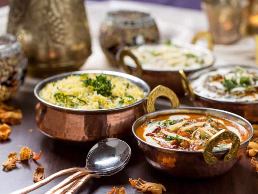 A selection of Indian curries and food in brass bowls.