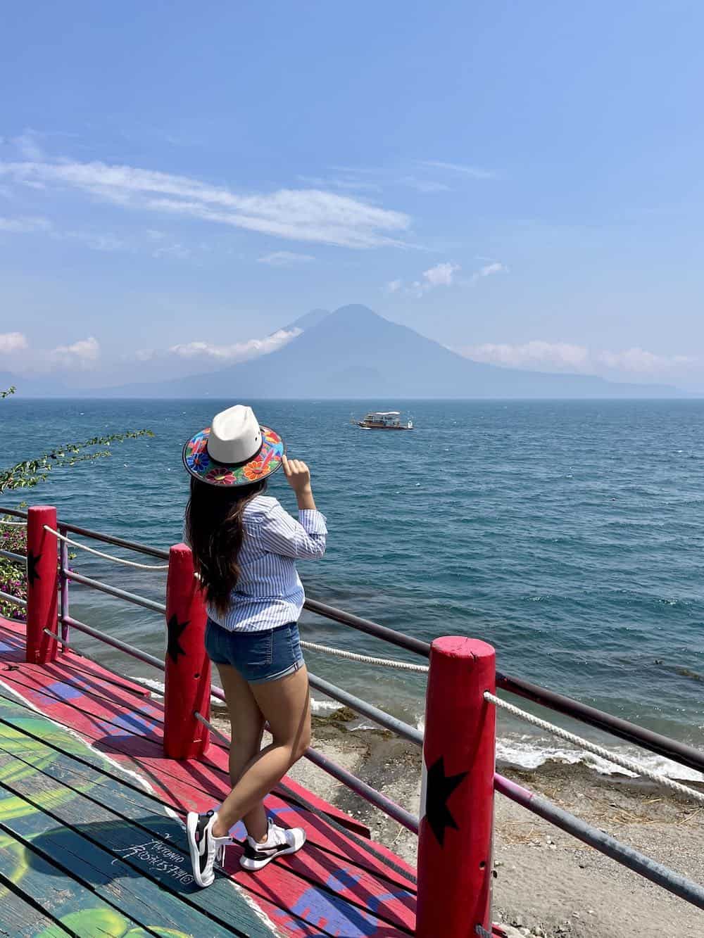 Young woman in Panajachel looking at Lake Atitlan with volcano in the distance. 