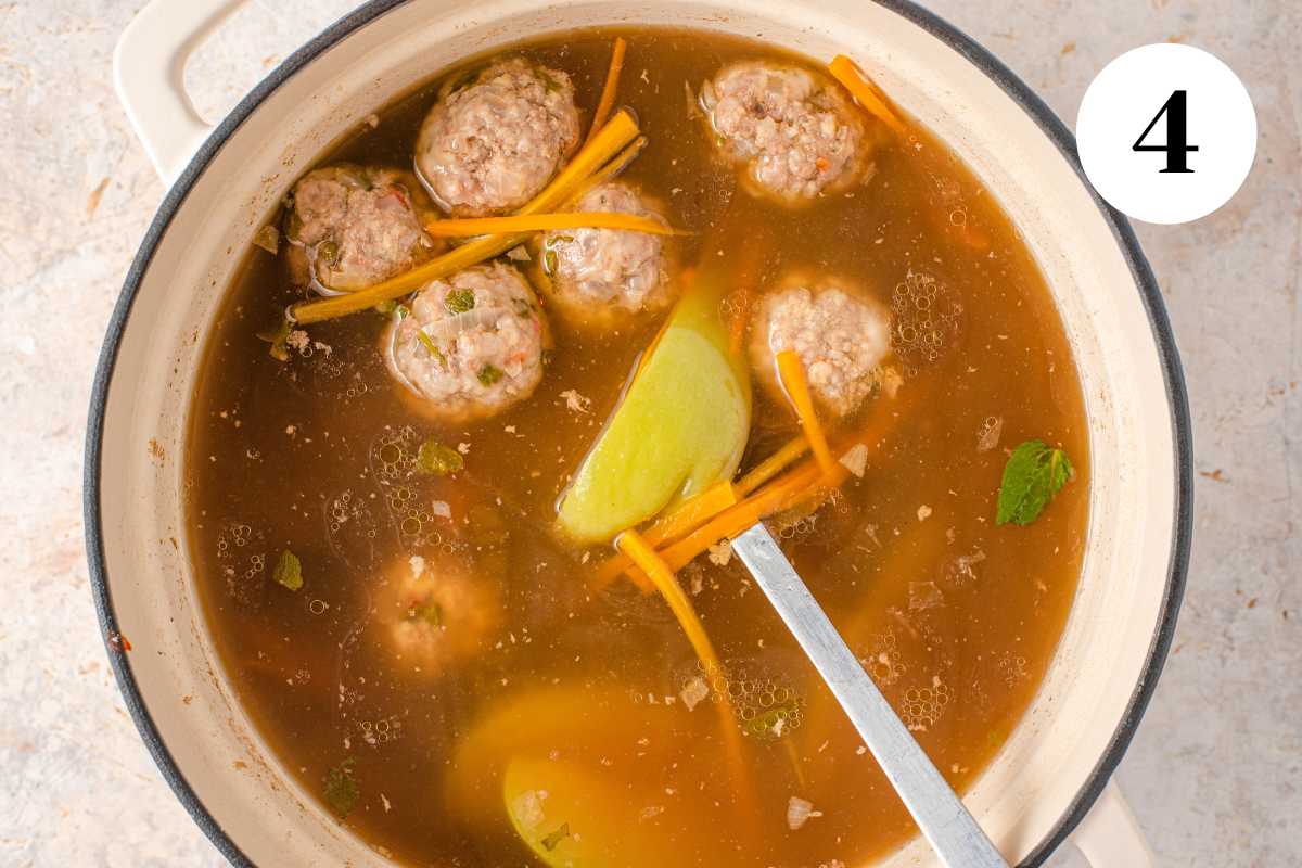 Skim to remove excess fat from meatball soup while cooking.
