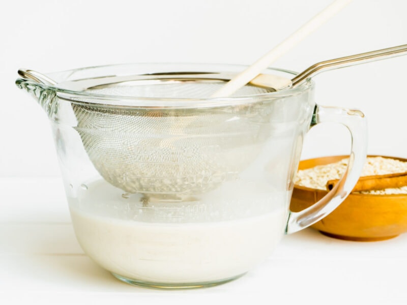 A strainer being used to separate the solids from the oat milk