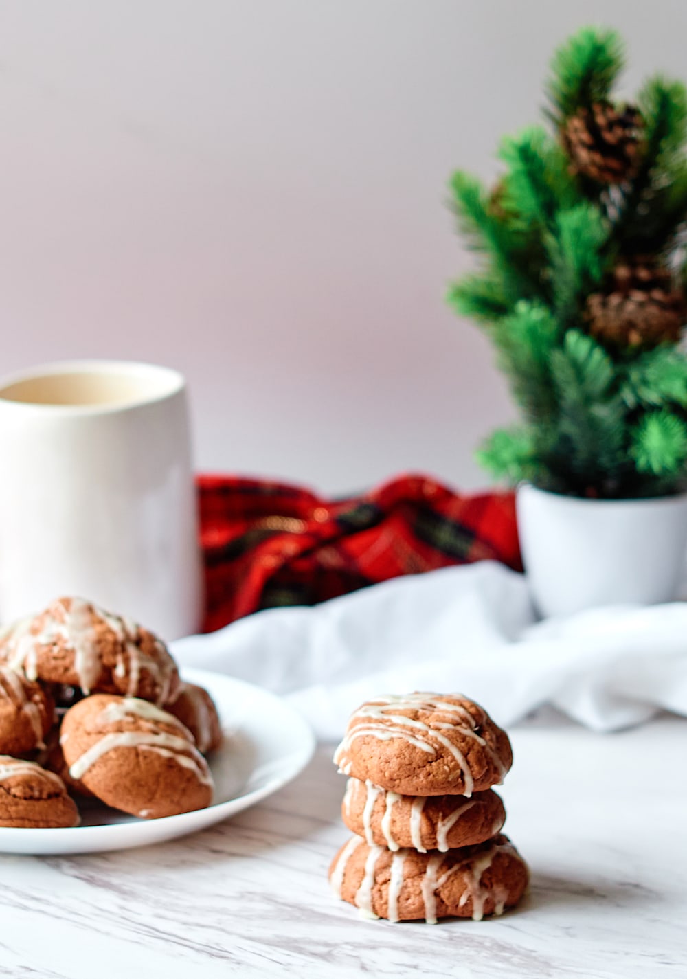 Eggnog cookies stacked in front of a Christmas tree. 