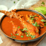 Kak ik Guatemalan turkey soup in a pottery bowl on a board.