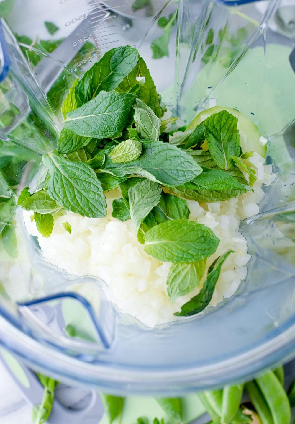 Onions and mint being added to a blender. 