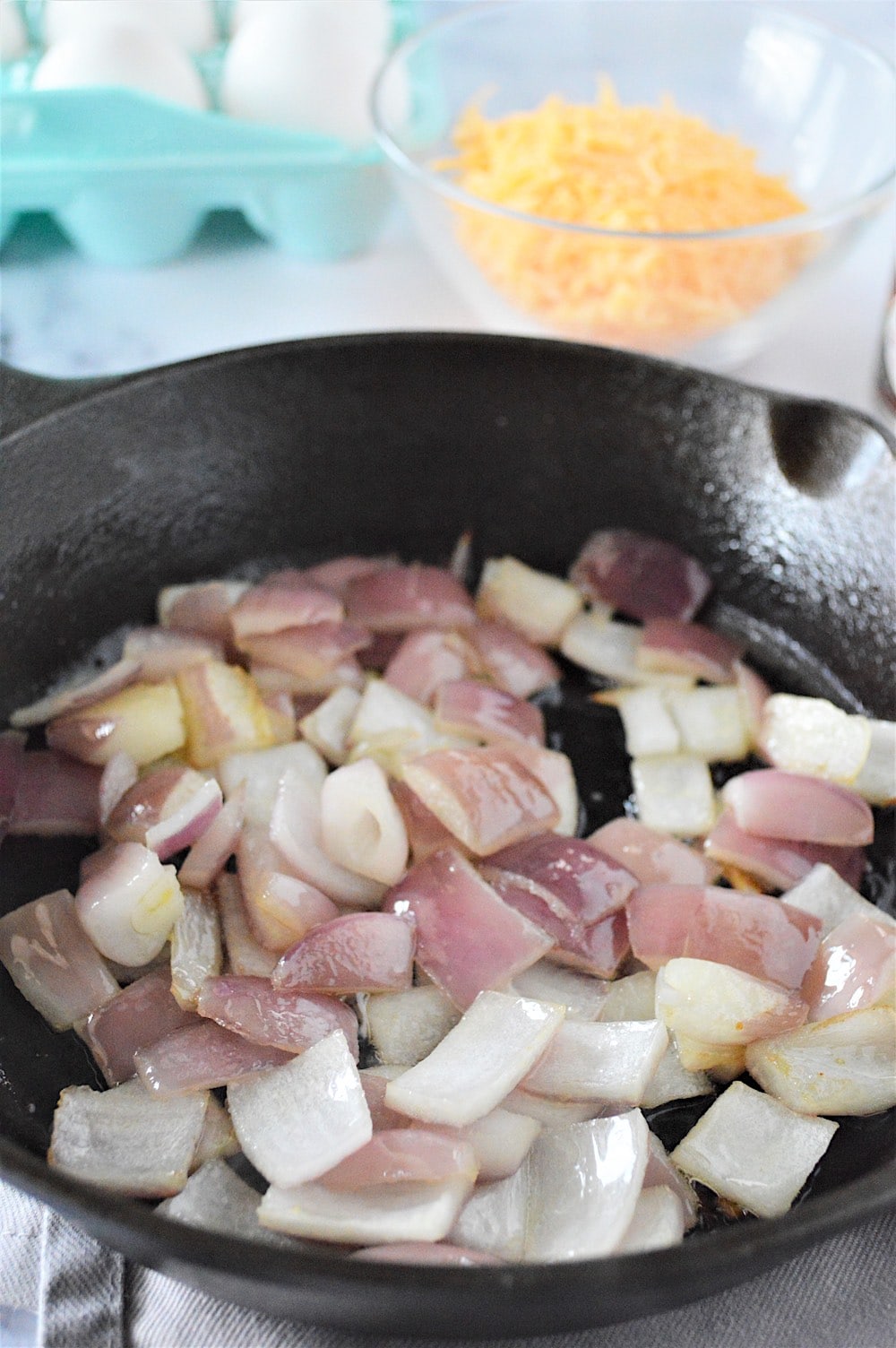 Red onions cooking in a skillet until translucent.