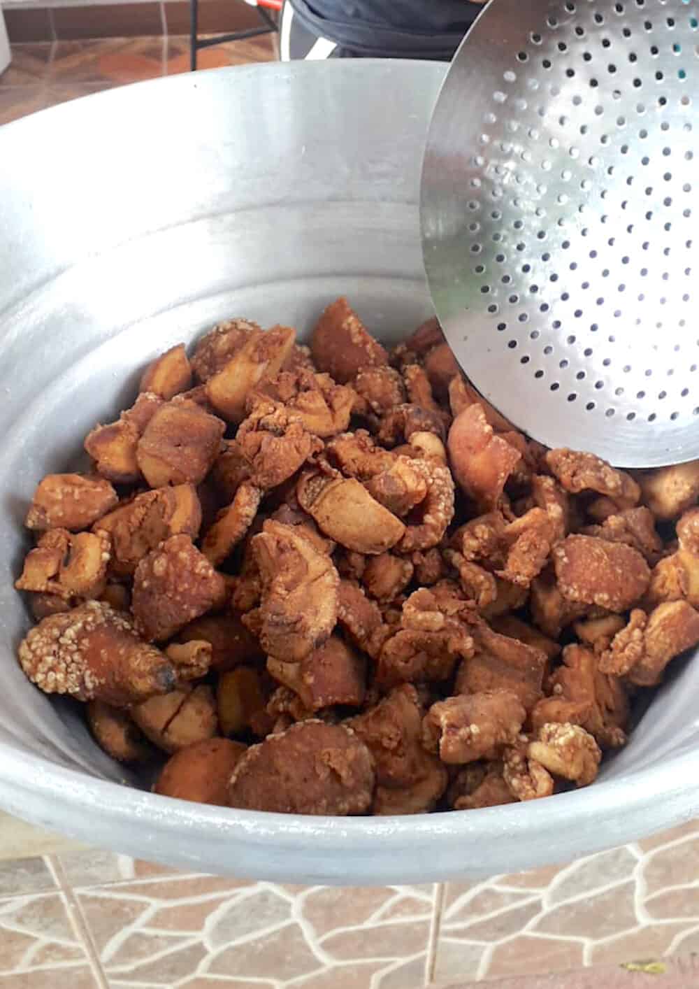 Crispy fried chicharrones in a metal pot.