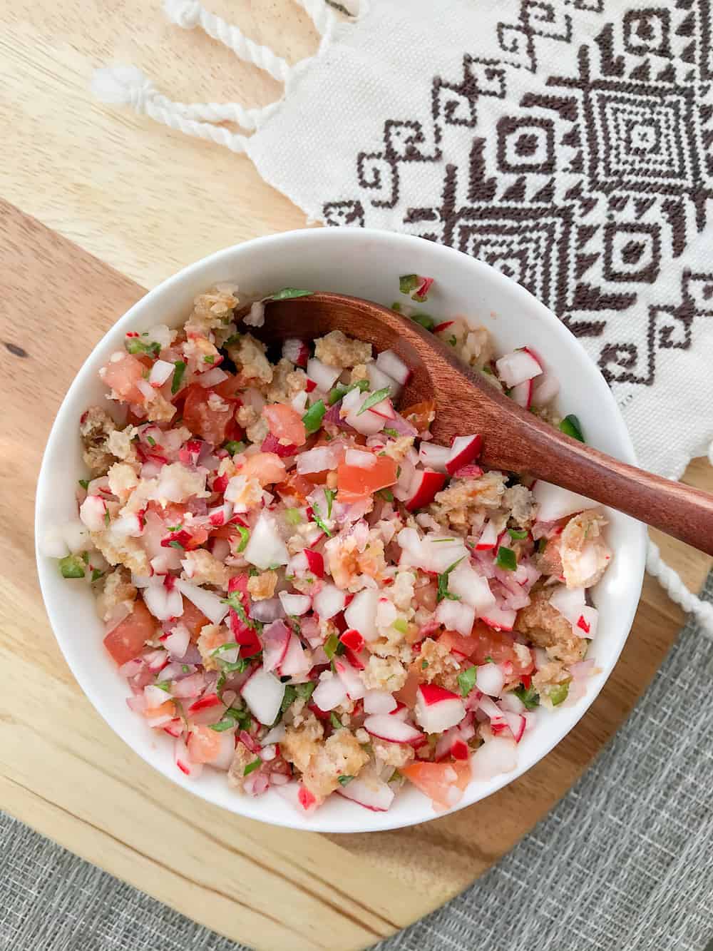 Chojin Guatemalan radish salad in a white bowl with a wooden spoon. 