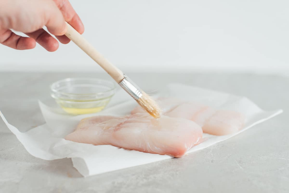 Brush applying vegetable oil to halibut fish.