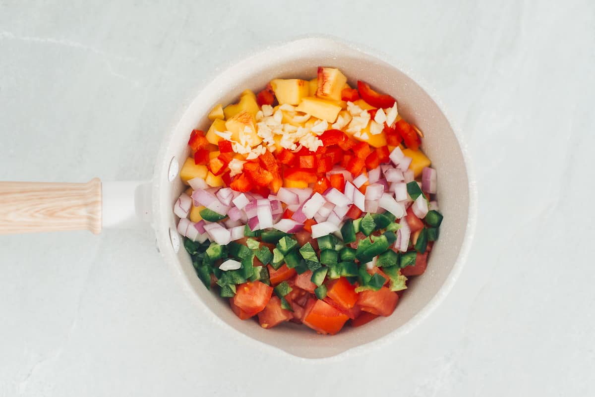 Chopped vegetablews and fruit for peach jalapeno sauce.