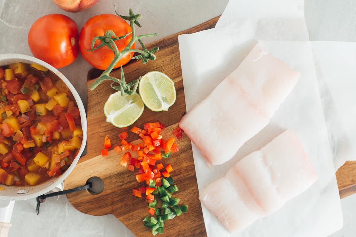 Tomatoes, peach and jalapeno peppers, lime and halibut ingredients.