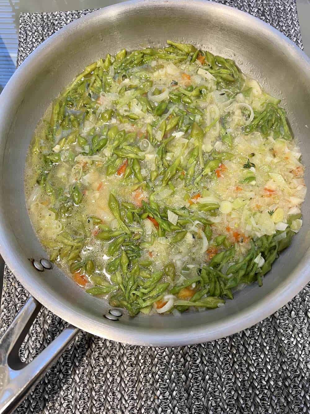 Add the strained chicken broth to the vegetables in the skillet.