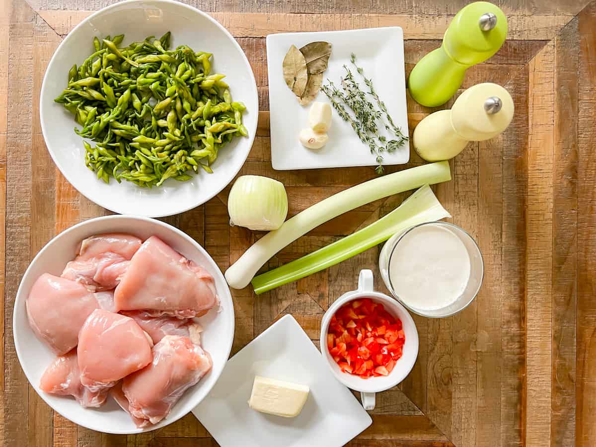 Ingredients for pollo con crema y loroco on a wooden board.