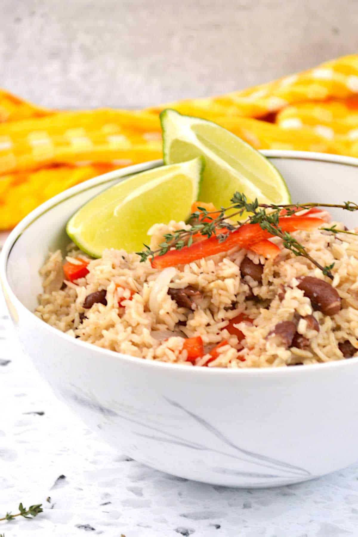 Garifuna coconut rice and beans in a white bowl with a yellow napkin.