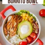 Overhead image of a chipotle chicken burrito bowl in a red serving dish on a white background.