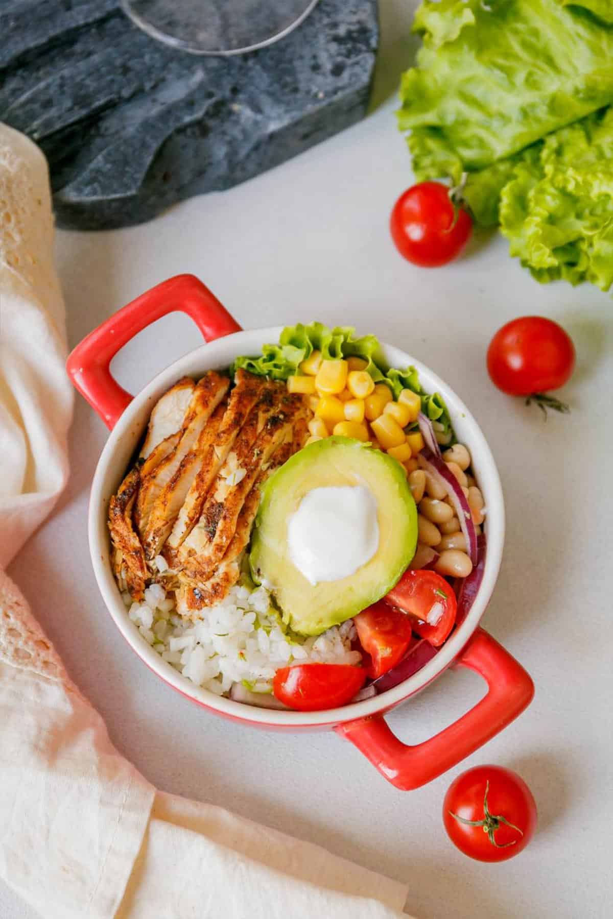 Overhead shot of chipotle chicken burrito bowl in a red dish.