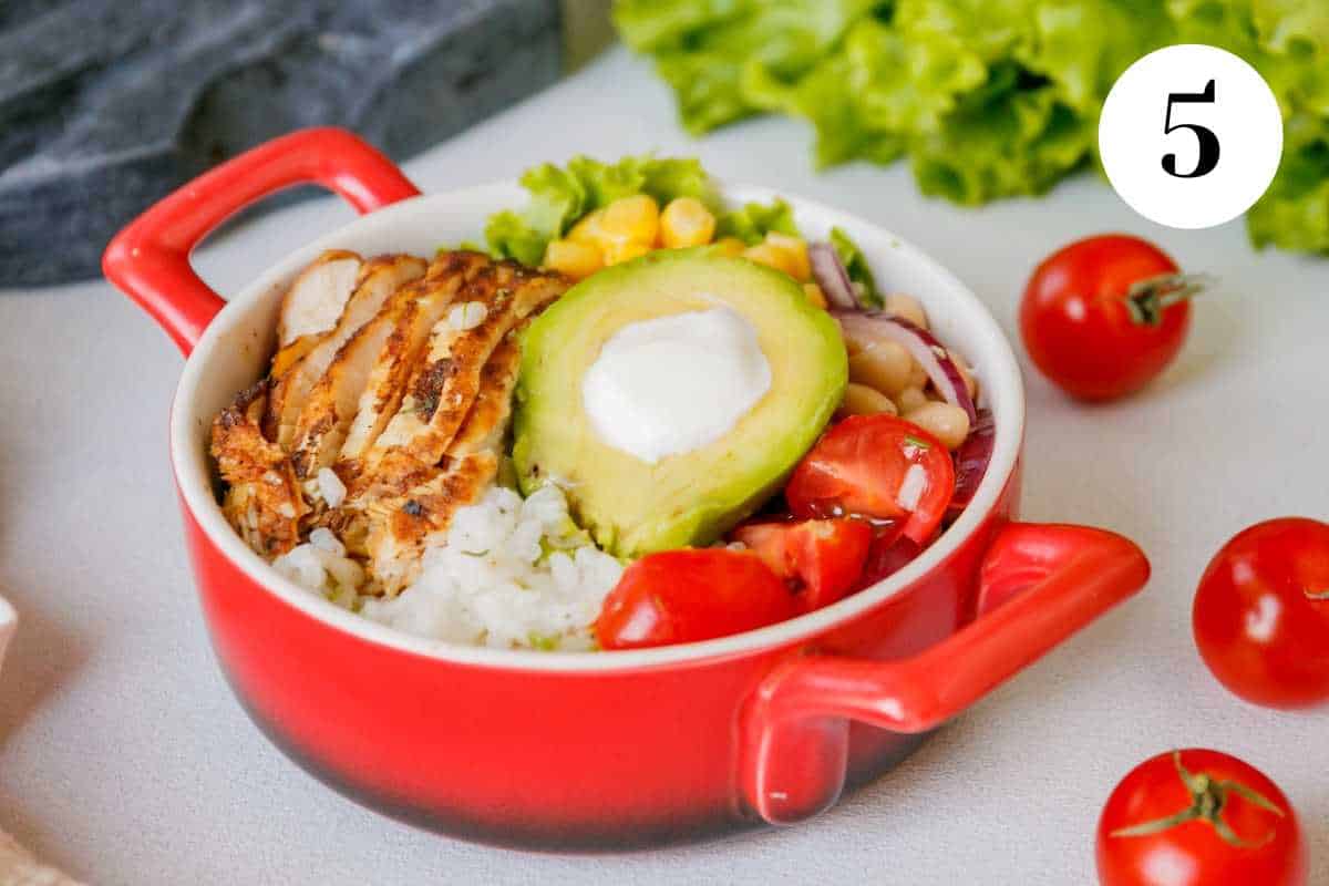 Cherry tomatoes and lettuce on a table with a chicken and rice burrito bowl.