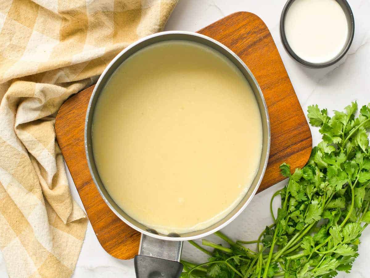 Blended soup in a pot on a wooden board.