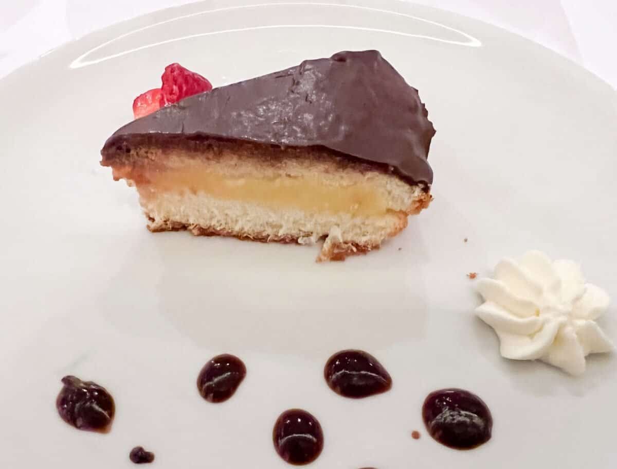 A slice of Boston Cream Pie on a white plate.