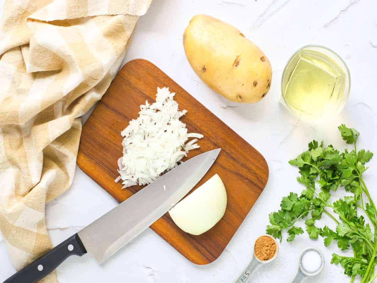 A knife with onions on a chopping board.
