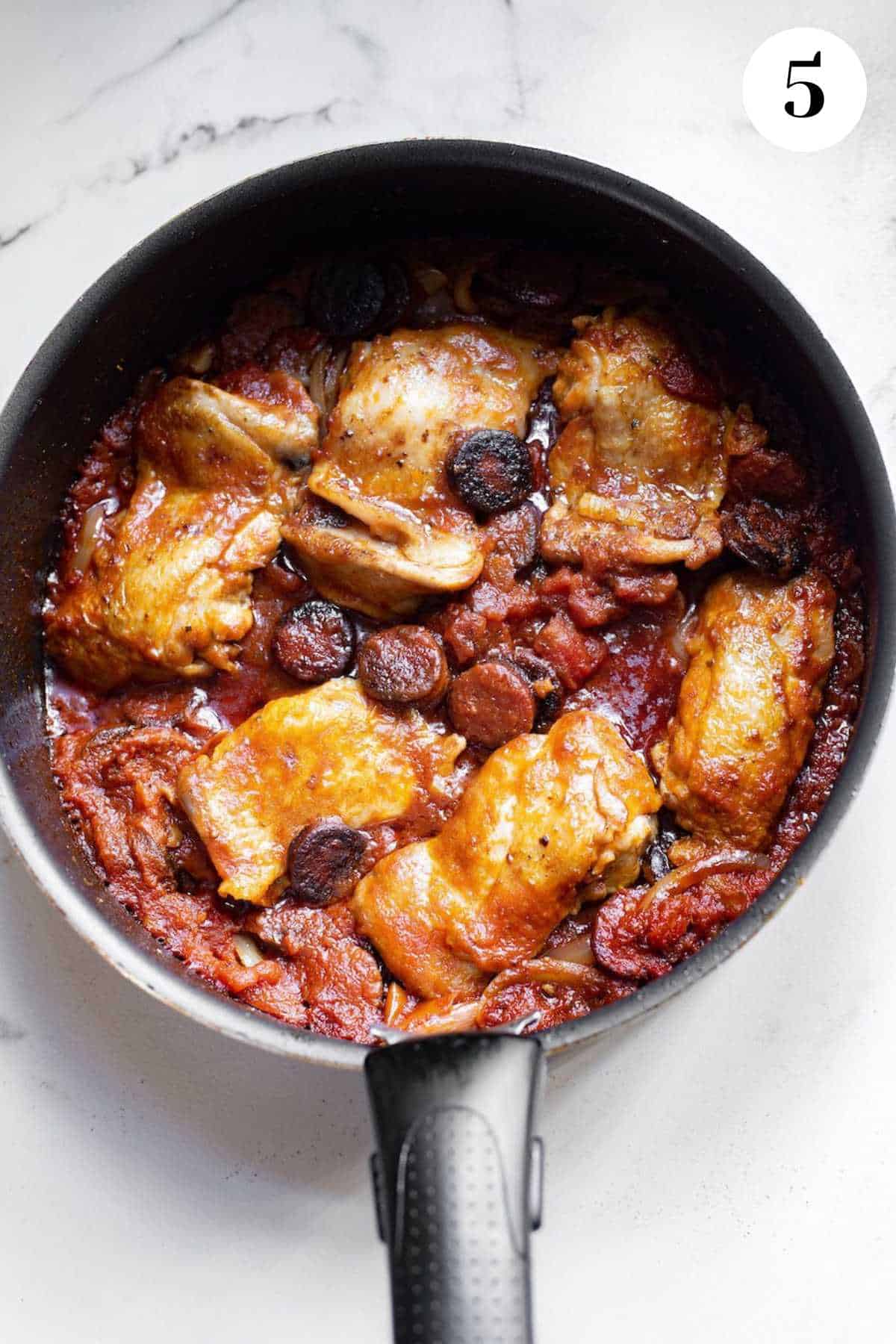 Chorizo and chicken stew Spanish simmering in a cast iron pan.