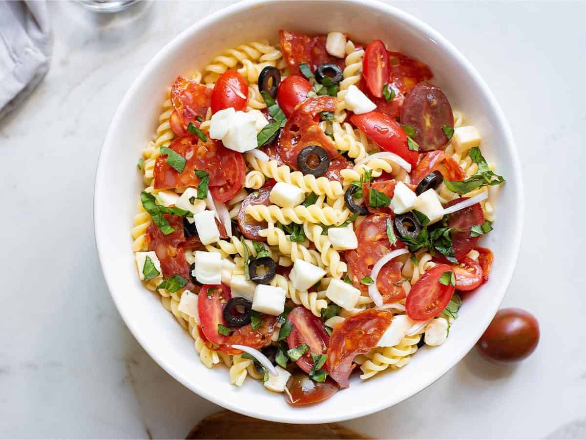 A white bowl of pizza Pasta salad.