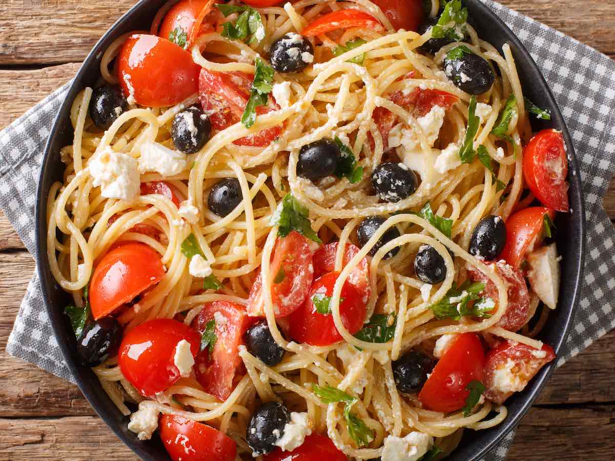Greek pasta salad in a black bowl.