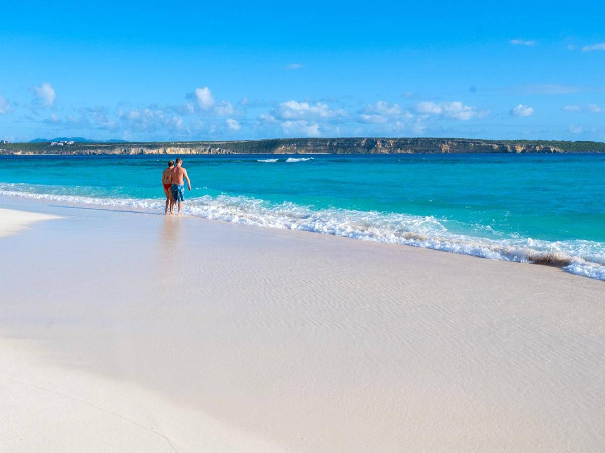Two people walking into the ocean. 