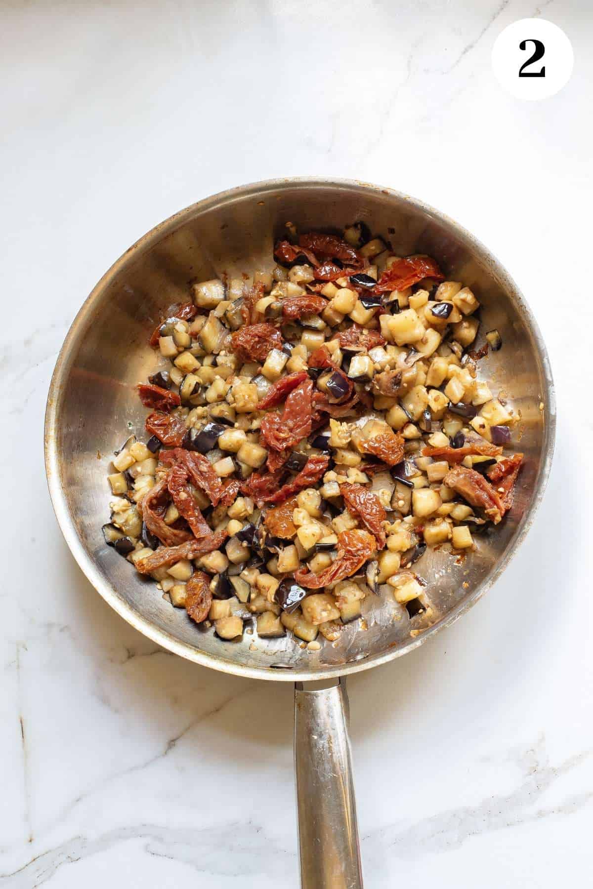 Sundried tomatoes and other ingredients added to the skillet with the eggplant.