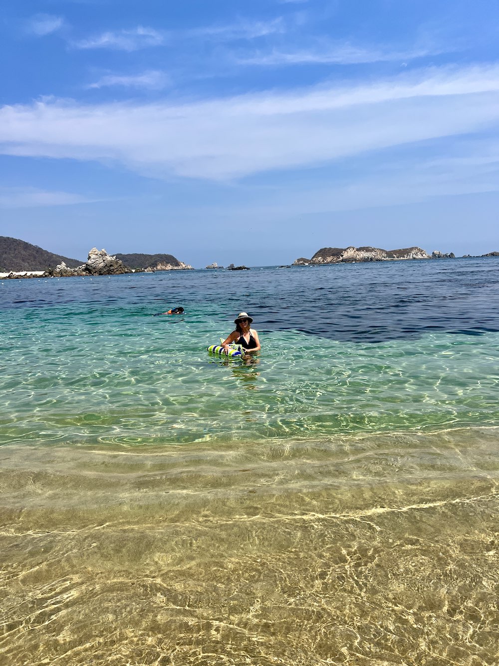 A person snorkeling and another person standing in clear water at Playa San Agustin, Huatulco)