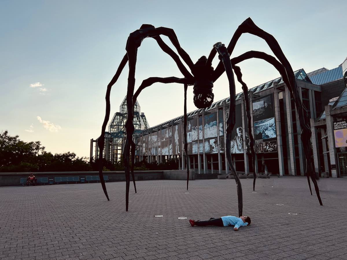 Boy striking a pose under the Maman statue in Ottawa.