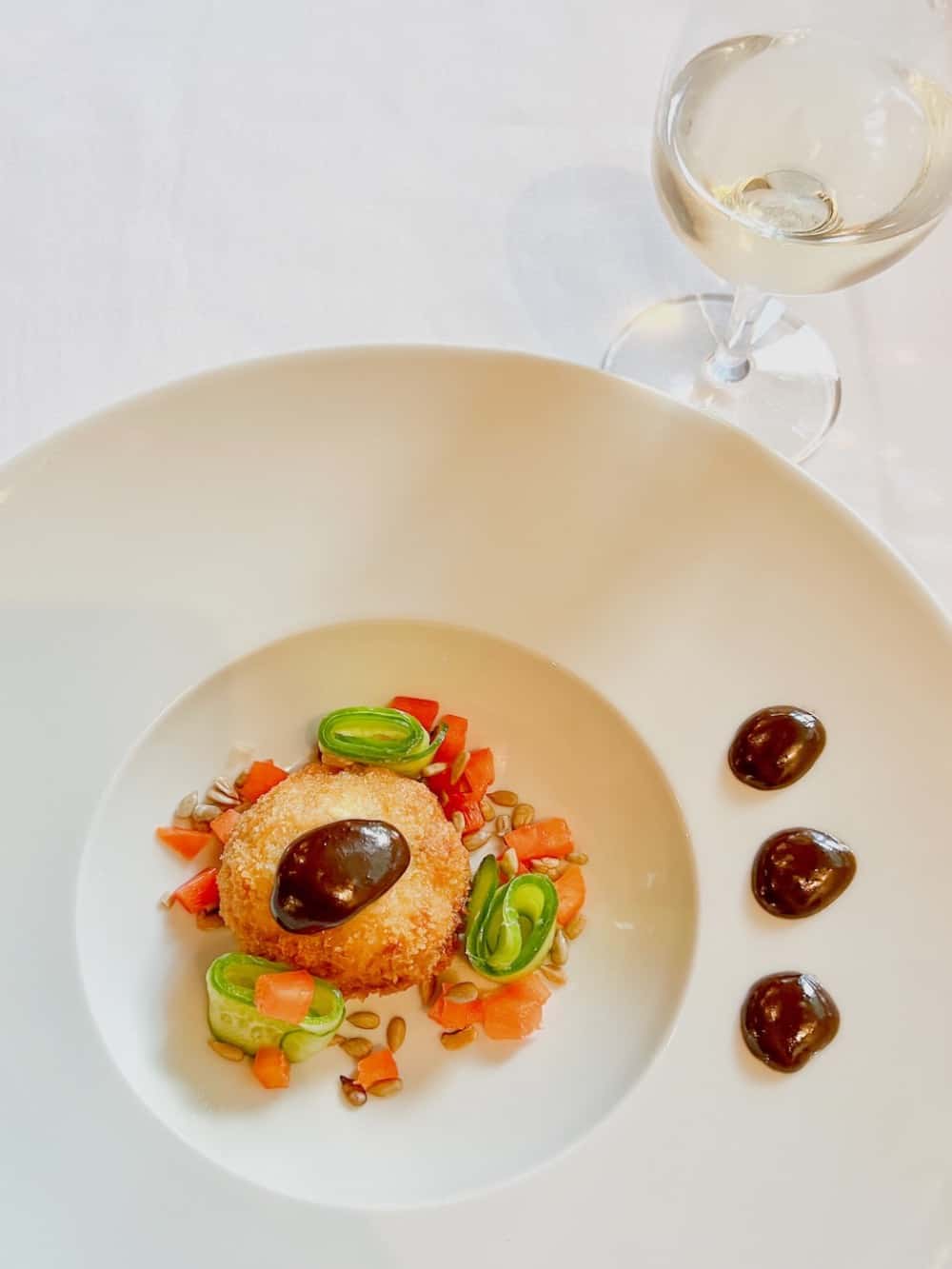 Salmon Croquette in white bowl with glass of wine.