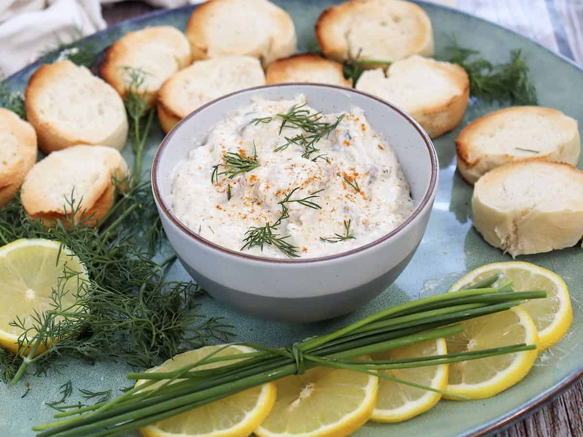 Creamy smoked herring dip in a pottery bowl with lemon slices and bread.