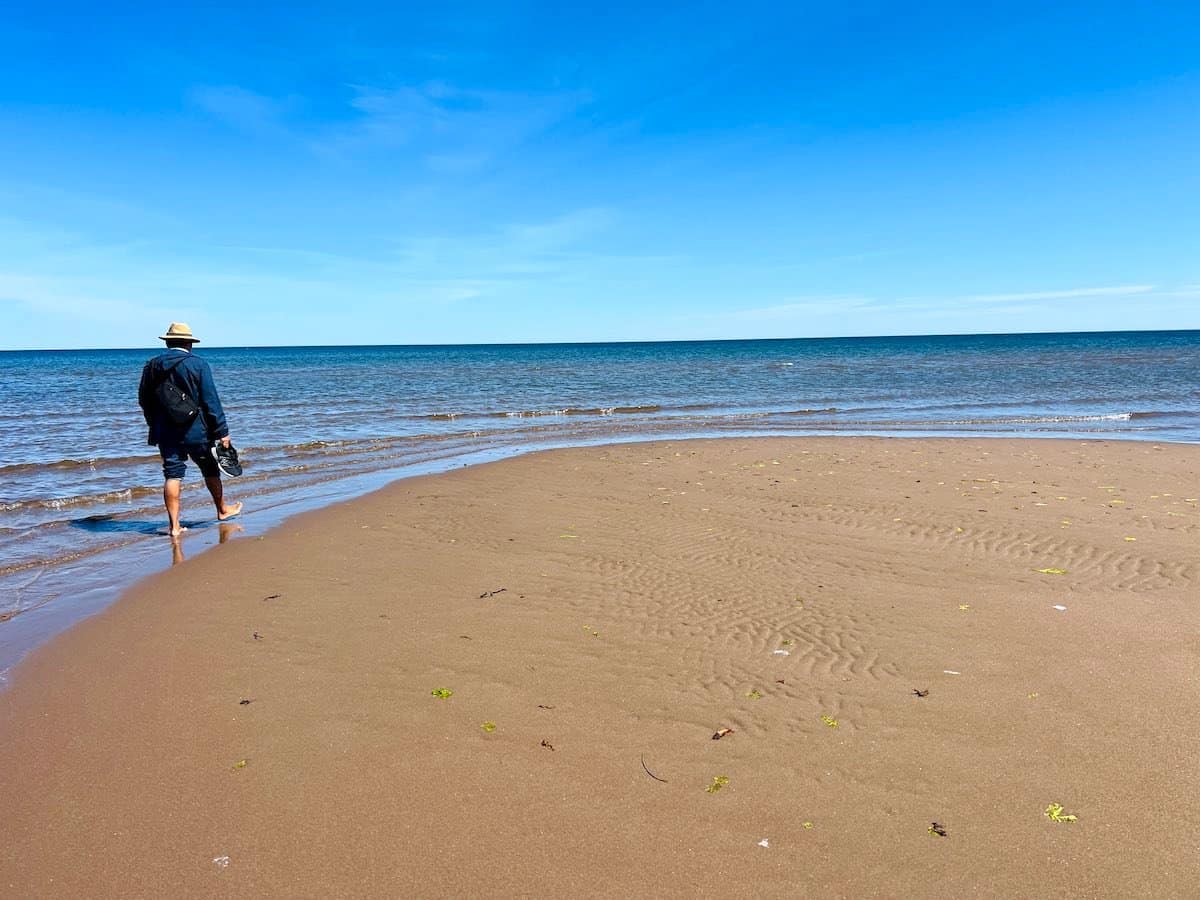 Man walking on the sand at Aboiteau Beach. 