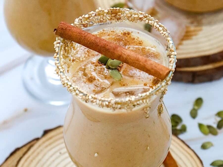 A glass of pumpkin spice horchata on a wooden board.