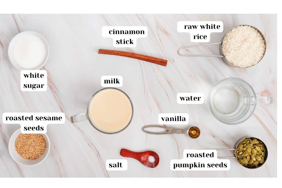 Labelled ingredients for horchata including raw white rice, water, milk, cinnamon stick, white sugard, vanilla, salt, sesame seeds and pumpkin seeds (roasted). 