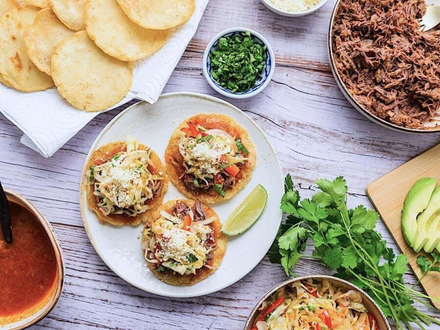 Assembled Guatemalan garnachas with meat, tomato and curtido topping.