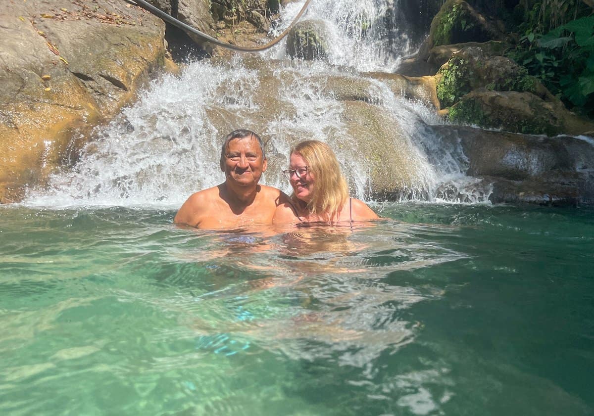 Two people swimming in the pools at the waterfall.