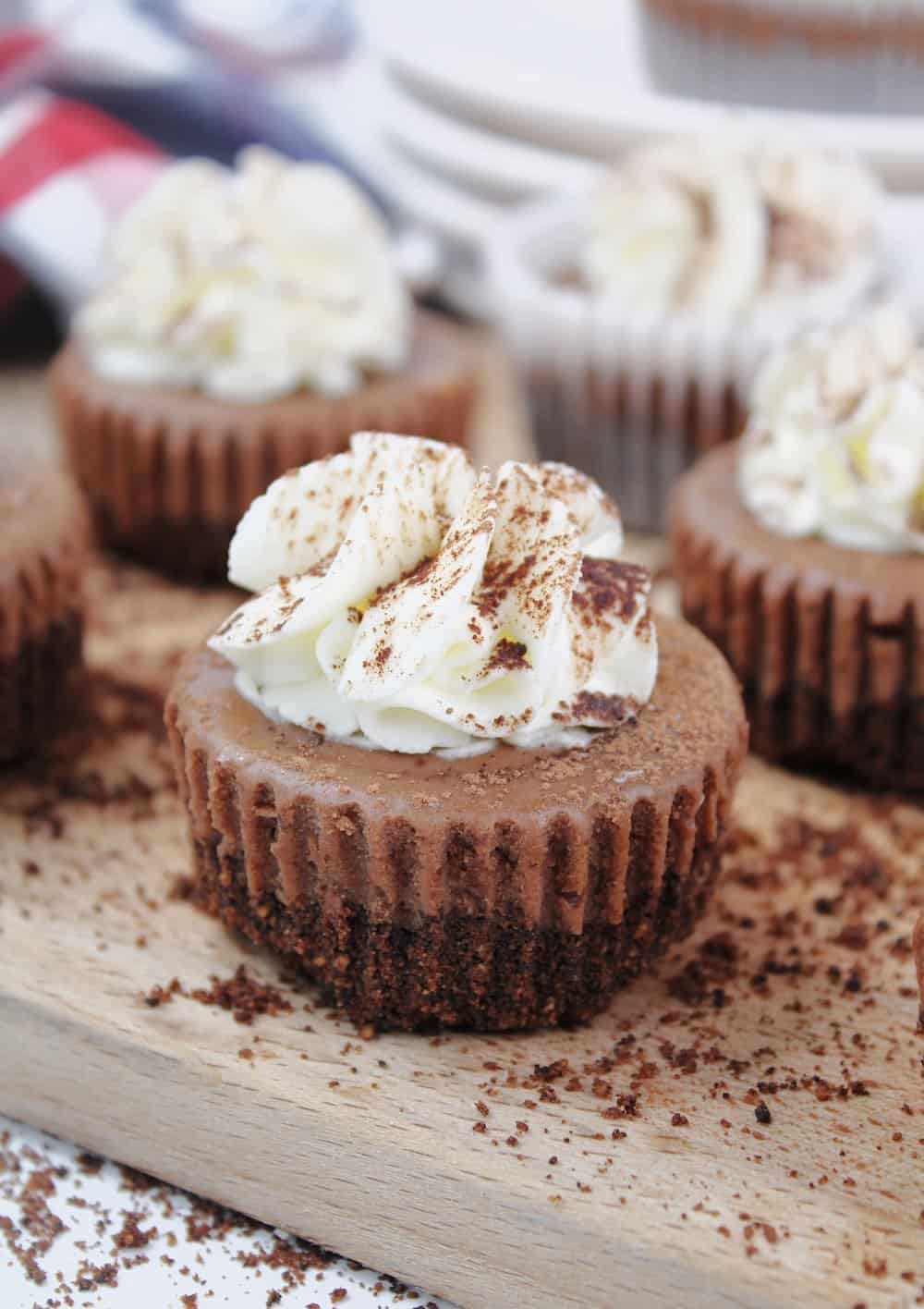 Portrait of mini cheesecakes made with Kahlua and chocolate topped with whipped cream. 